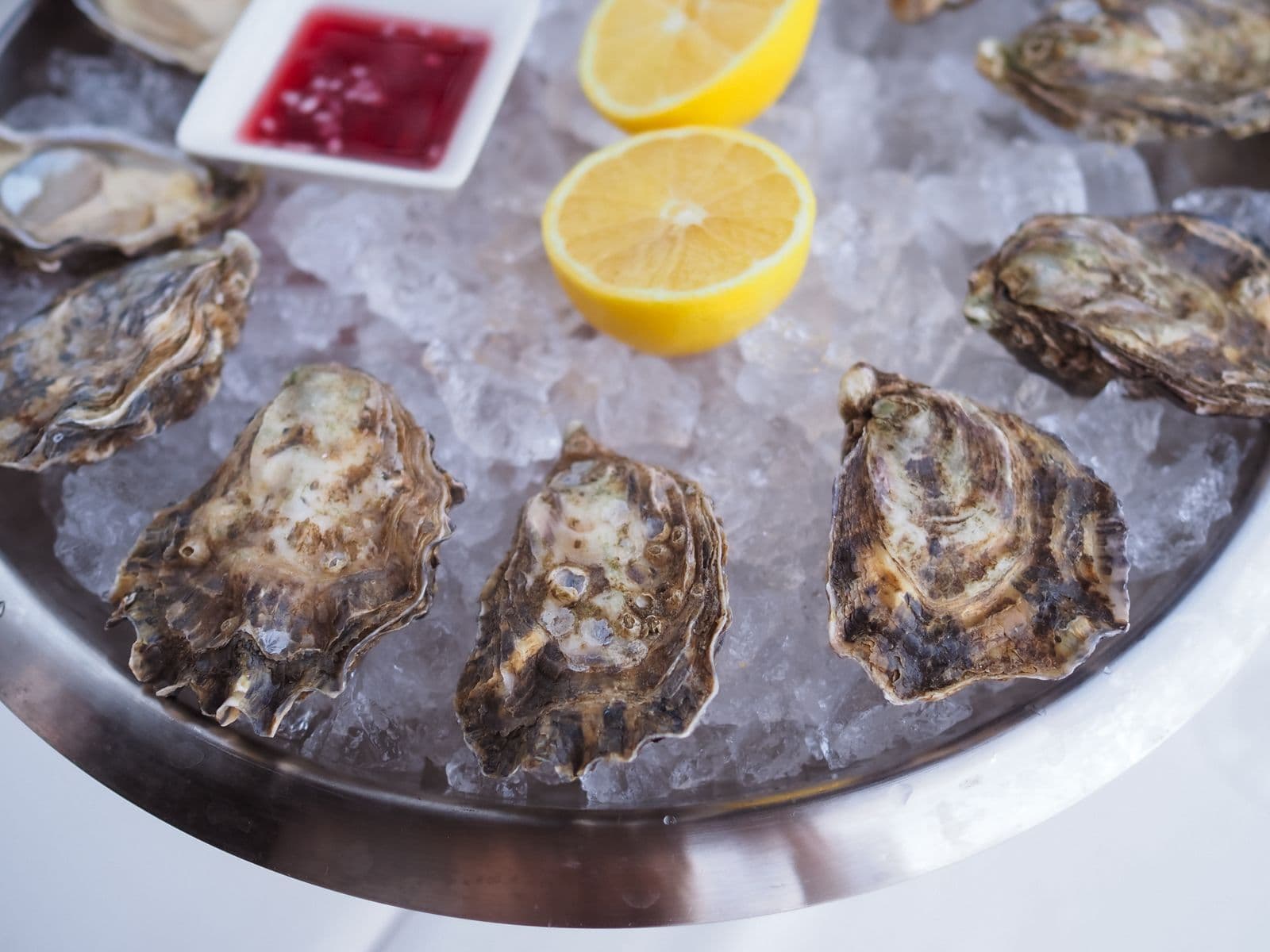 Plateau d'huîtres sur glace, citron et mignonette, servi au bar.